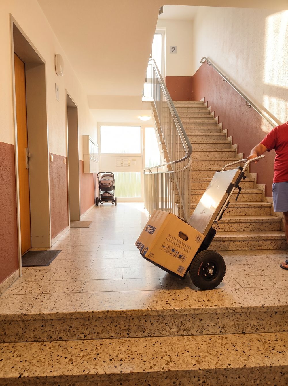 Elektrische Sackkarre mit Karton im Treppenhaus eines Mehrfamilienhauses